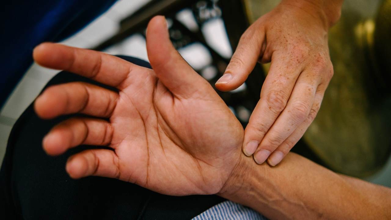 Close of an acupuncturist's fingers pressing on a patient's wrist to read their pulse.